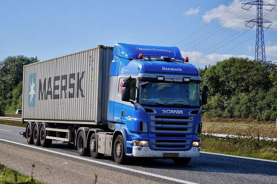 Shipping container being delivered by truck
