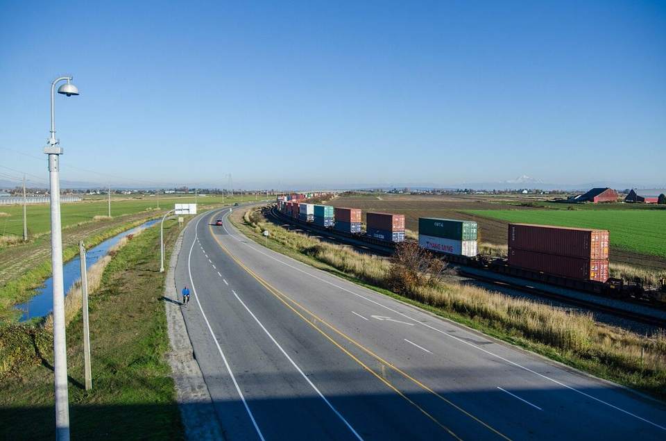 Container train running alongside an open highway